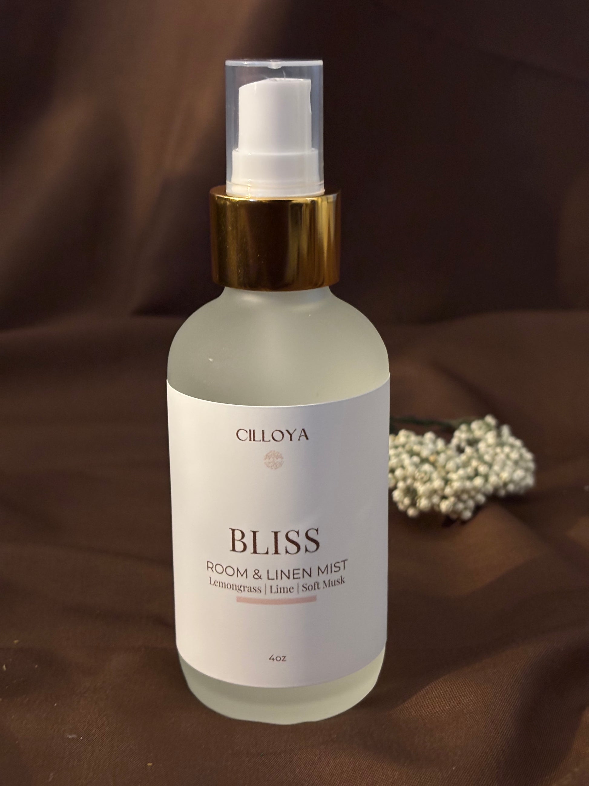Cilloya Bliss Room and Linen Mist in a 4oz frosted glass bottle with a gold neck, featuring notes of Lemongrass, Lime, and Light Musk on a dark brown backdrop.