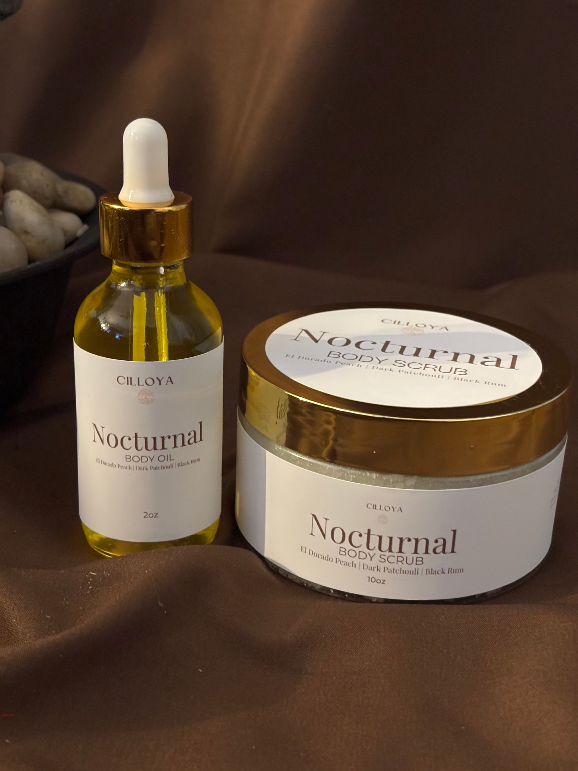 Cilloya Radiance Experience gift set featuring a 2oz Nocturnal Body Oil and a 10oz Nocturnal Body Scrub on a dark brown backdrop