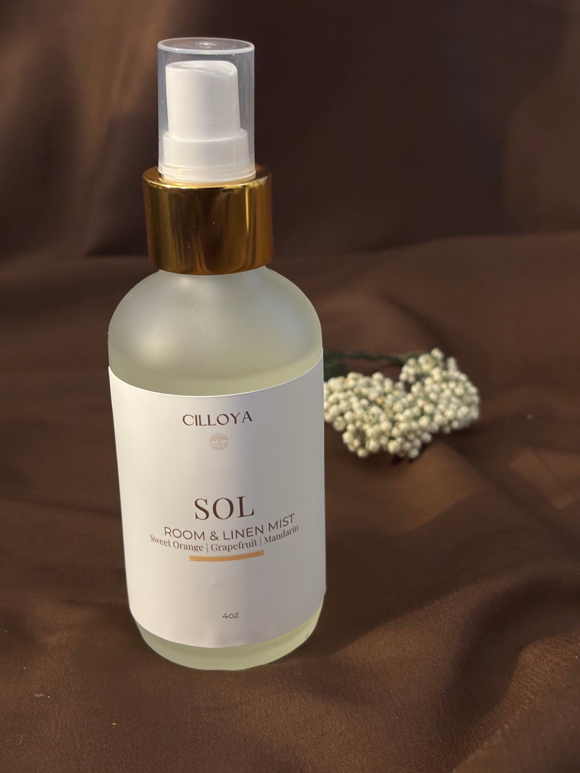 Cilloya Sol Room and Linen Mist in a 4oz frosted glass bottle with a gold neck, featuring notes of Sweet Orange, Mandarin, and Grapefruit on a dark brown backdrop.