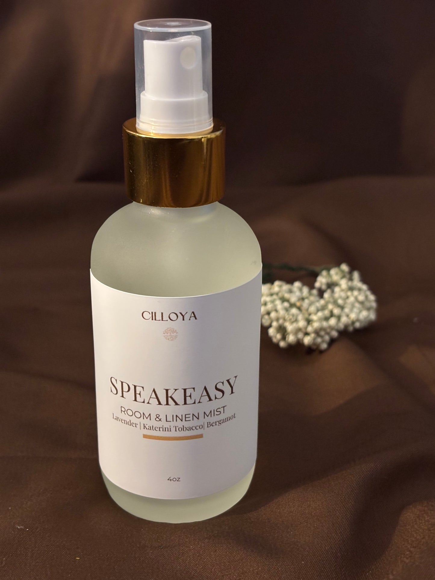 Cilloya Speakeasy Room and Linen Mist in a 4oz frosted glass bottle with a gold neck, featuring notes of Lavender, Tobacco, and Bergamot on a dark brown backdrop.