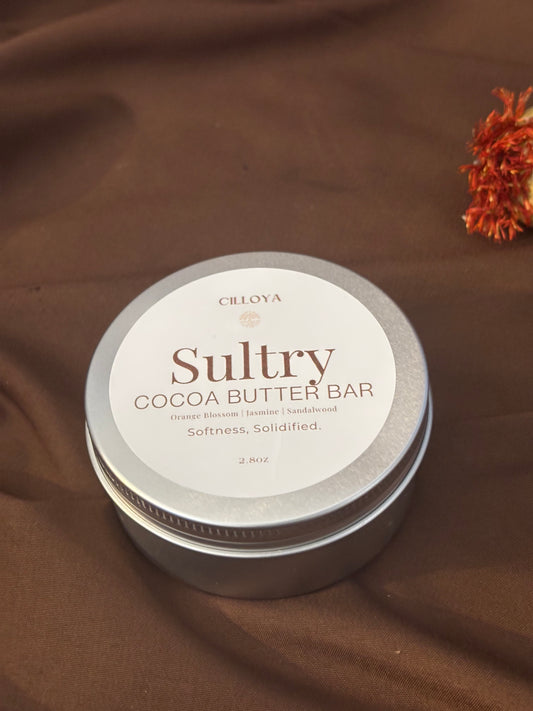 Cilloya Sultry Cocoa Butter Bar in a silver round tin with a top label on a dark brown background