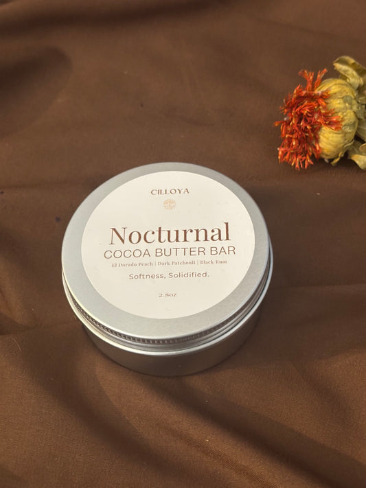 Cilloya Nocturnal Cocoa Butter Bar in a silver round tin with a top label on a dark brown backdrop